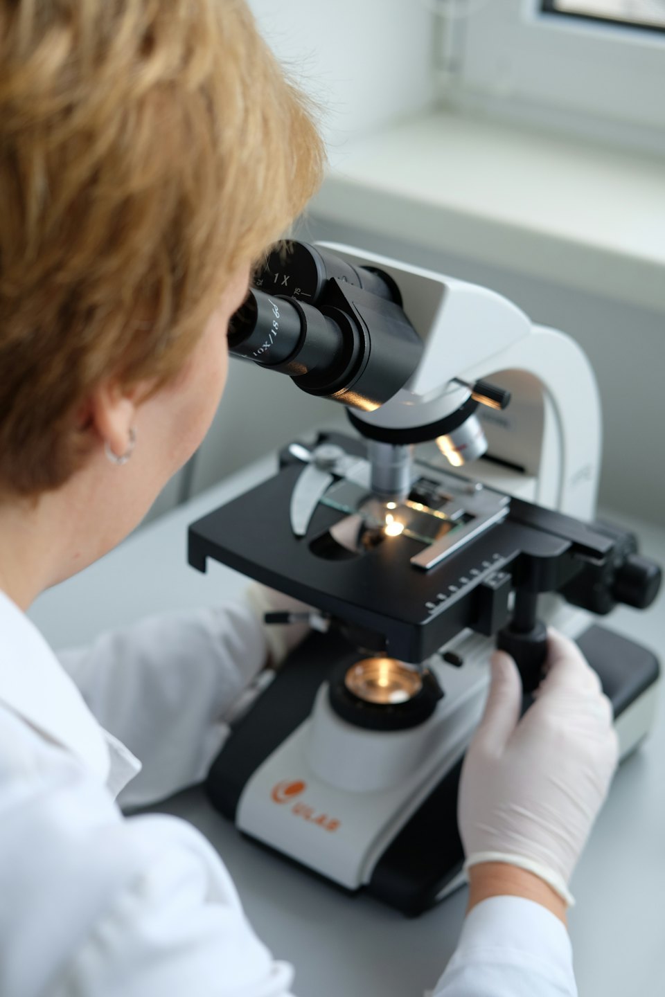Scienziato che esamina un campione al microscopio in laboratorio.