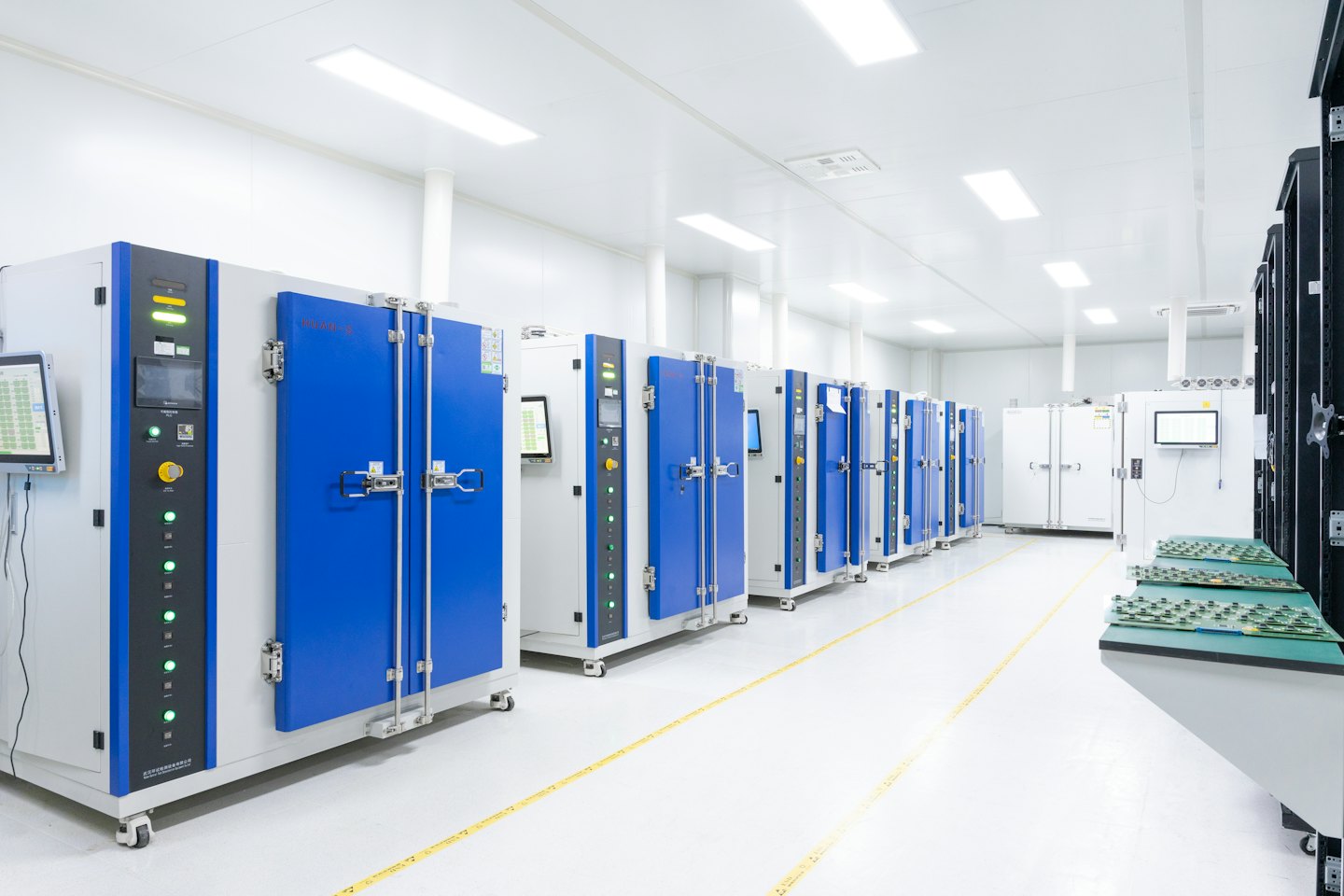 File di camere di prova ambientali bianche con porte blu in un laboratorio pulito.